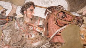 Dettaglio del celebre mosaico di Alessandro Magno in battaglia, con lo sguardo intenso rivolto in avanti. L’immagine è utilizzata per evocare il fascino leggendario attribuito ai suoi occhi, uno nero e uno azzurro secondo Plutarco, e per introdurre il tema dell’eterocromia come segno di forza, mistero e dualità tra umano e divino.